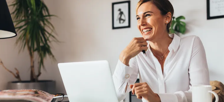 A remote working woman is smiling while working with her laptop